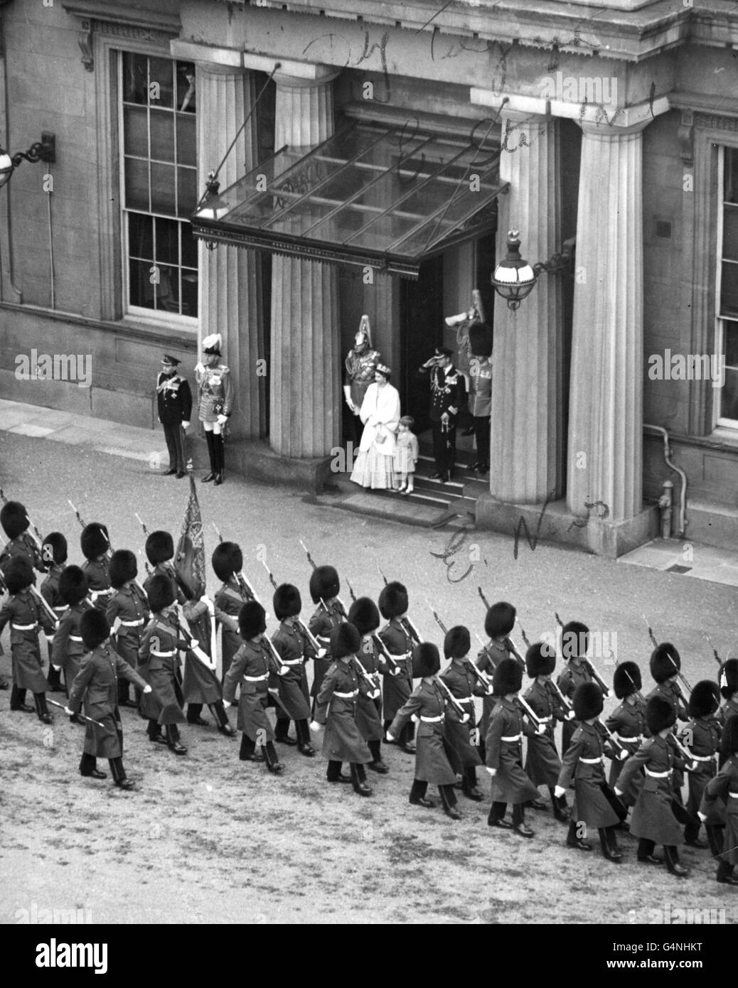 Queen Elizabeth II with Prince Charles beside her, watches troops of her Brigade of Guards march past in the Quadrangle of Buckingham Palace, as the Duke of Edinburgh in naval uniform, salutes. The Queen and Duke had just returned from the House of Lords, where the Queen opened the first Parliament of her Reign. Stock Photo