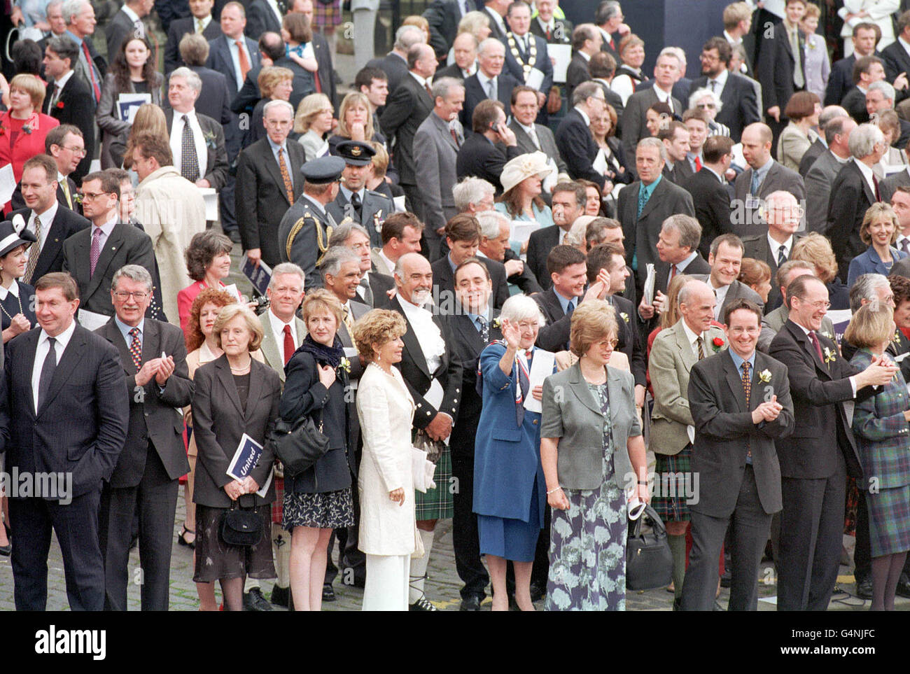 Alex Salmond MSP (centre of crowd, second row), leader of the Scottish National Party, Scottish actor Sean Connery (kilt, left of Salmond), his wife Micheline (cream jacket & trousers) and other MSPs watch the parade after the official opening of the Scottish Parliament in Edinburgh. Stock Photo