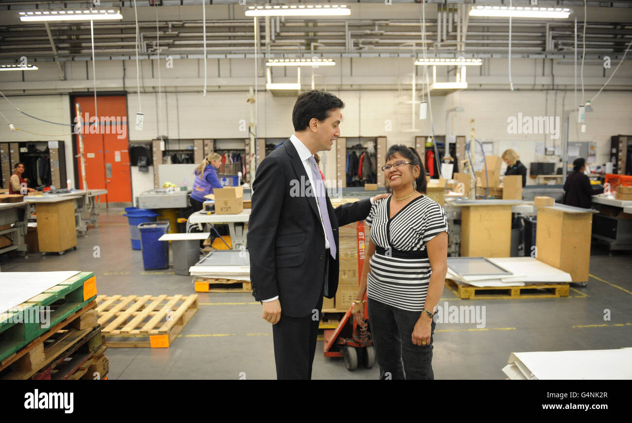 Labour leader Ed Miliband speaks with staff member Shanta Patel, 55, who has been at manufacturing firm Kesslers International for 22 years during his visit to Stratford, east London. Stock Photo