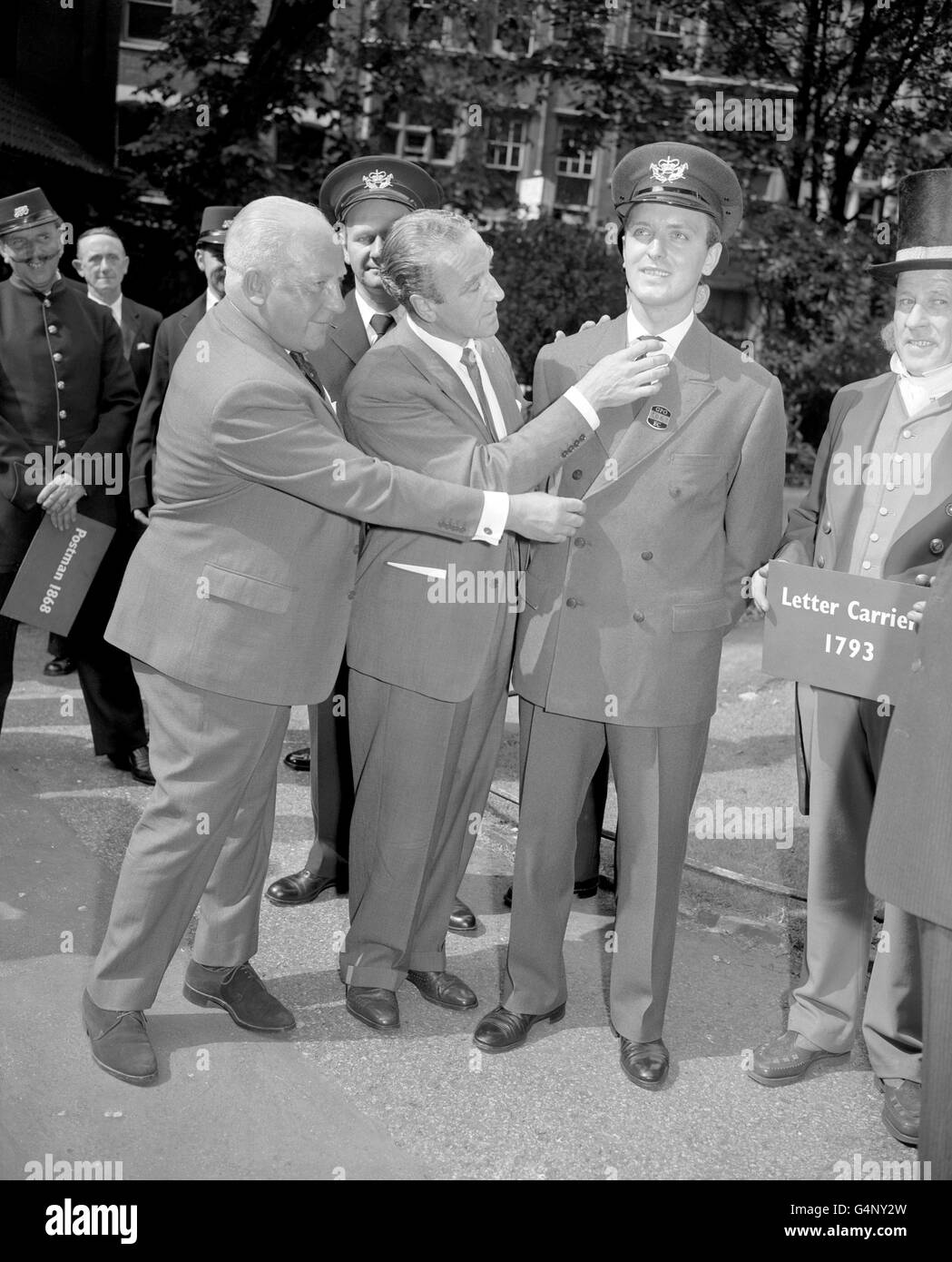 One of the proposed new uniforms for Britain's postmen is viewed by Postmaster-General, Mr Ernest Marples (centre) and Mr Langley Powe, whose firm designed it, at St Martin's-le-Grand, London. The uniform, in grey material and double breasted, is worn by model Simon Hill. Stock Photo