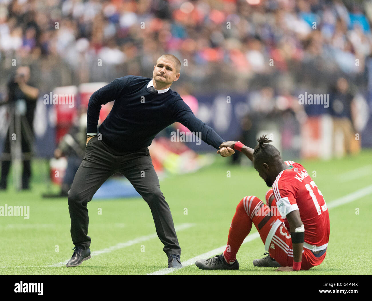 Vancouver, Canada. 18 June, 2016. Vancouver coach Carl Robinson helping up New England Revolution forward Kei Kamara (13) up after a fall.Vancouver Whitecaps vs New England Revolution, BC Place Stadium. Final Score New England wins 2-1. Credit:  Gerry Rousseau/Alamy Live News Stock Photo