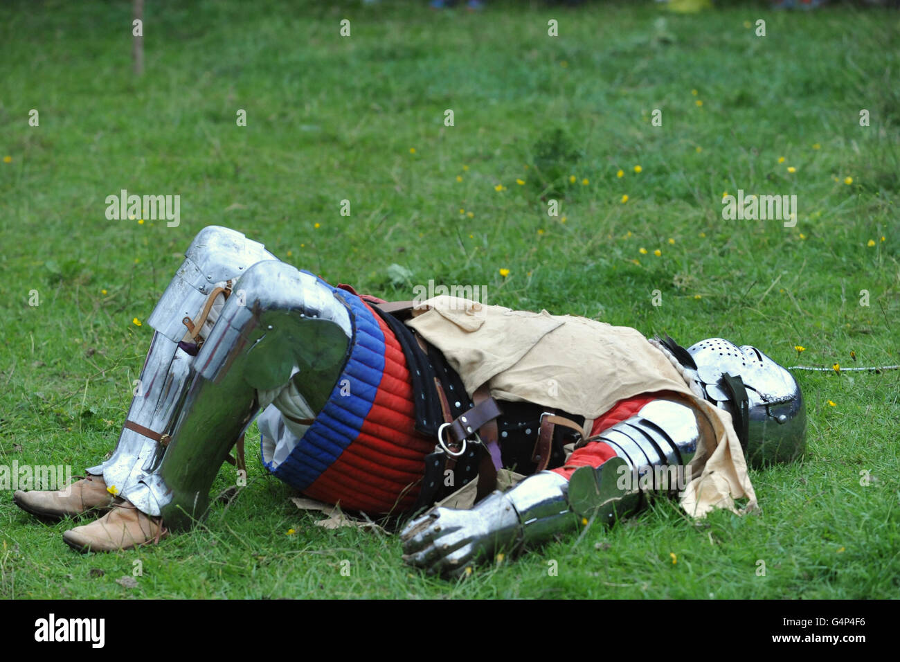 Greenwich, London, UK. 18th June, 2016. A re-enactor dressed as a medieval man at arms lying on the grass during a re-enactment in Greenwich, London, UK. The 'Grand Medieval Joust' was held at Eltham Palace, an English Heritage property which was the home of King Henry VIII as a child. The event aims to give an insight into life at the palace during the medieval period. Credit:  Michael Preston/Alamy Live News Stock Photo