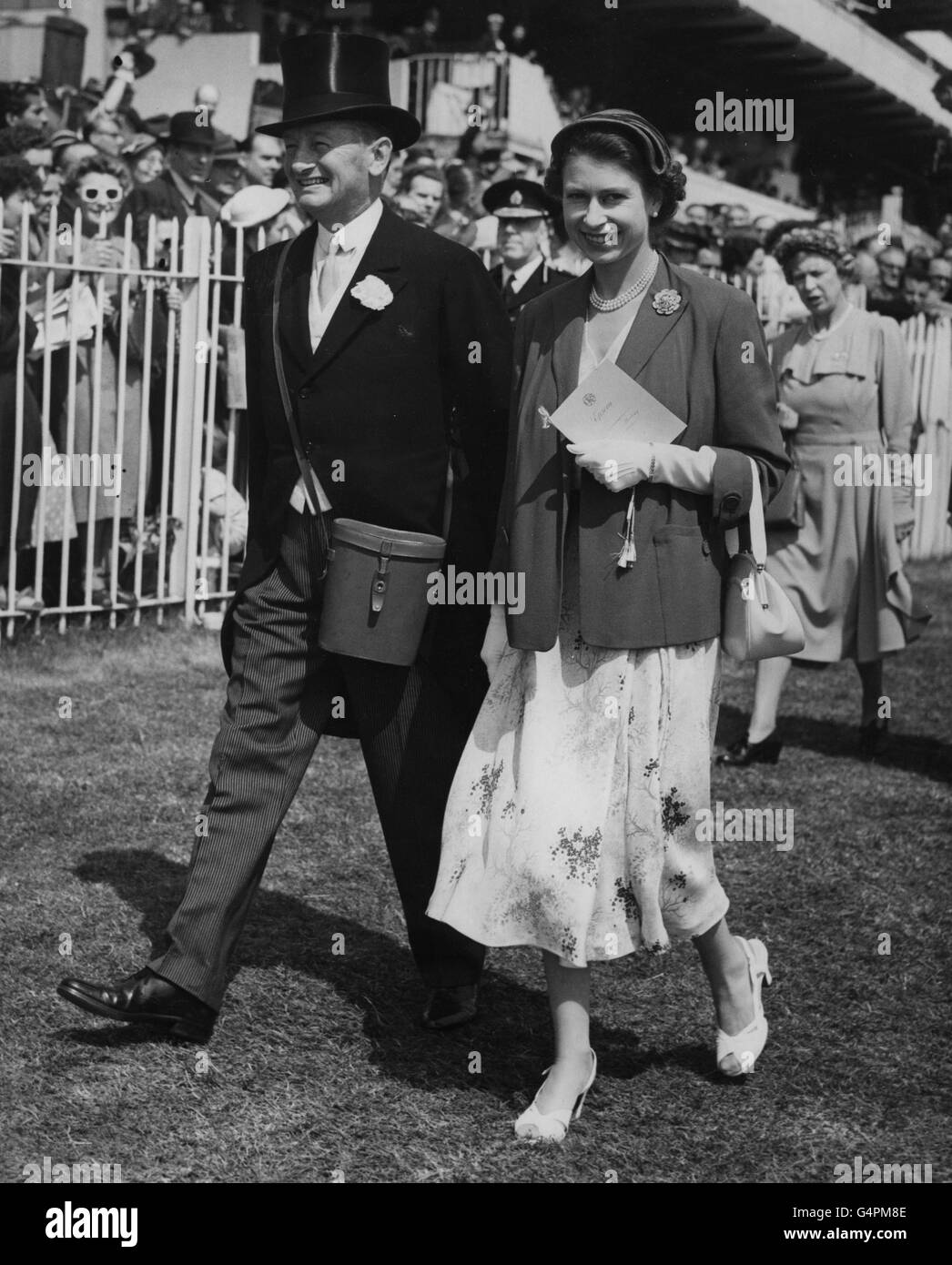 Queen Elizabeth II, accompanied by Sir Humphrey de Trafford, walks to the paddock to see her filly Angel Bright before the Oaks Stakes Stock Photo