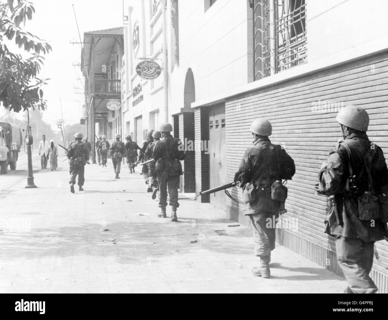 SUEZ 1956: Strung out close to the buildings, an Allied patrol moves through an almost deserted street in Port Said, key town at the northern end of the Suez Canal, held by the British and French troops. Stock Photo