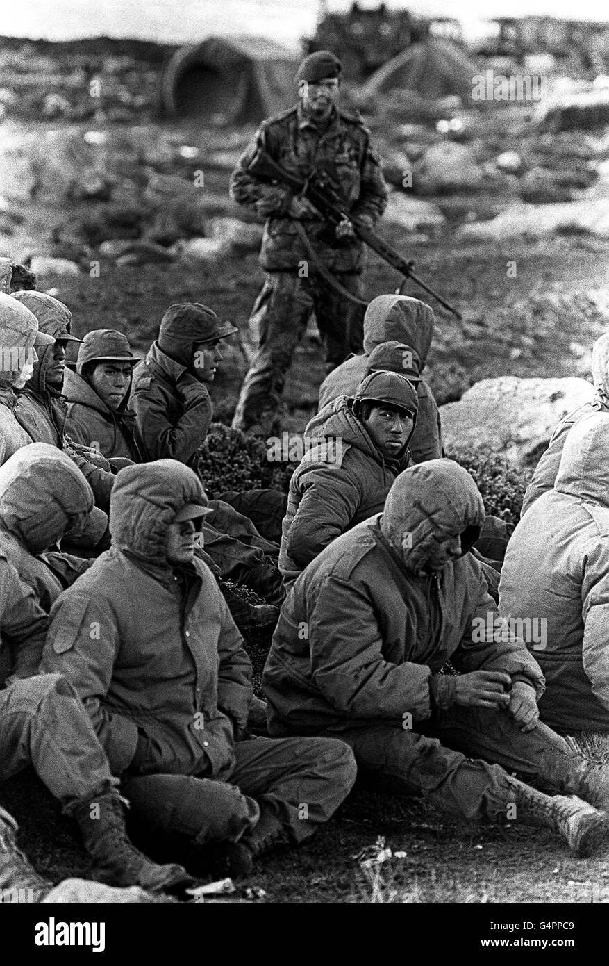 THE FALKLANDS WAR: Argentinian soldiers captured at Goose Green are guarded by a Royal Marine as they await transit out of the area. Goose Green was captured by men of the Parachute Regiment (2 Para). Stock Photo