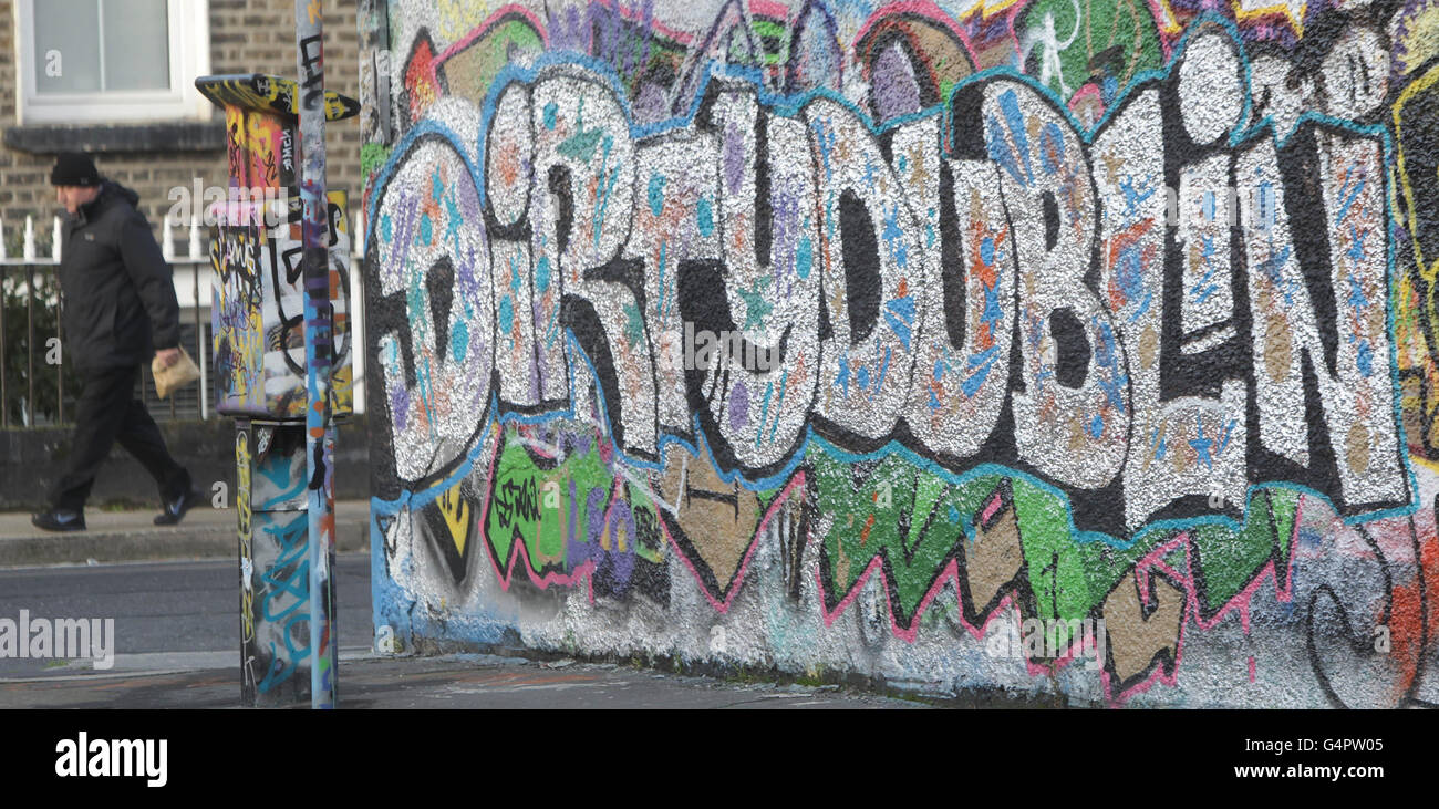 A man walks past graffiti daubed on the wall of the Windmill Lane Studios, belonging to the band U2, in central Dublin . Stock Photo