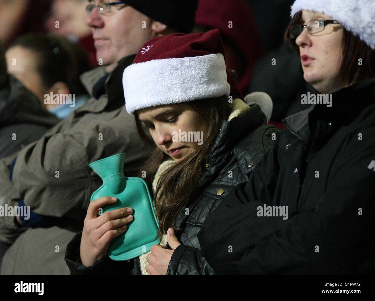 Soccer - Barclays Premier League - Bolton Wanderers v Aston Villa - Reebok Stadium. A female fan warms up with a hot water bottle in the stands Stock Photo