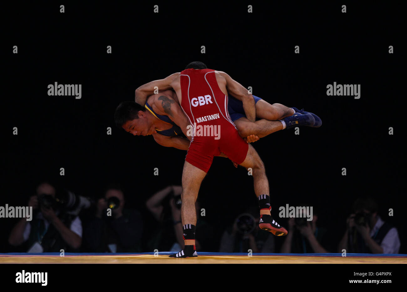 Great Britain's Krasimir Krastanov lifts China's Mude Qi during his win in the Bronze medal bout at 55kg during the London Olympic Games 2012 Test Event at the Excel Arena, London. Stock Photo