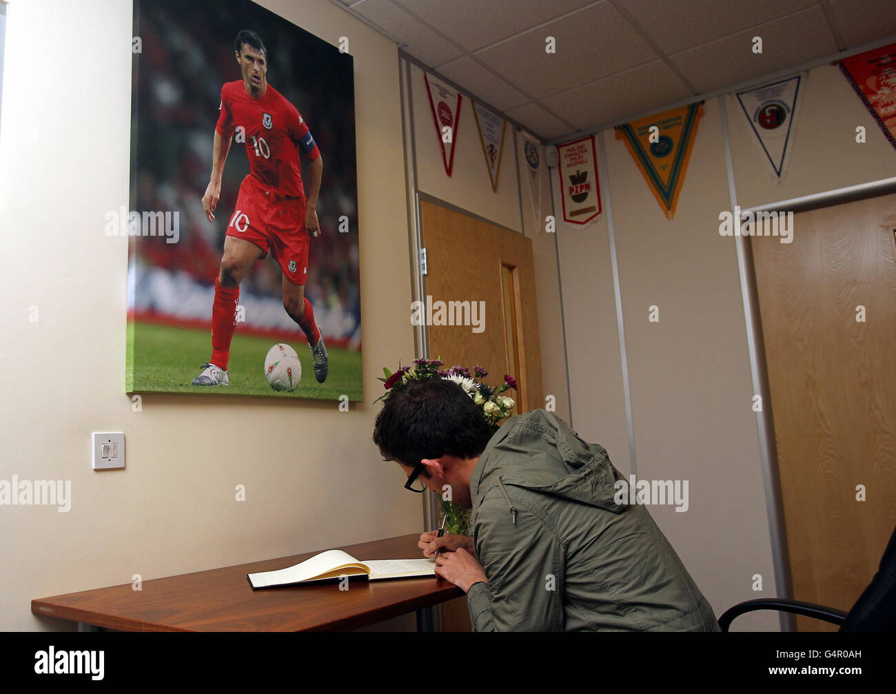 A fan signs the book of rememberance for Gary Speed inside the Welsh Football Association ofiices, Cardiff. Stock Photo