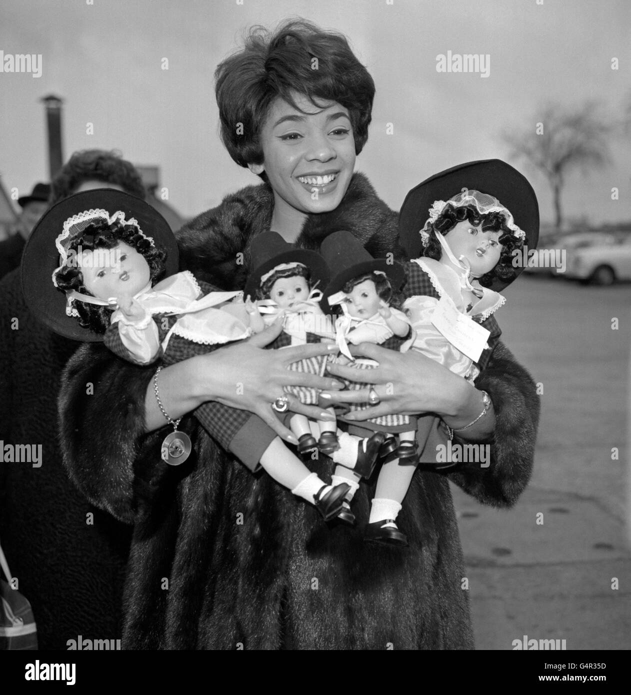 Singer Shirley Bassey has her arms full of dolls in Welsh national costume at London Airport, where she was about to board a Qantas Liner for Australia. On behalf of the Lord Mayor of Cardiff, her native city, she will present the dolls to the towns in which she appears during her Australian tour. Stock Photo