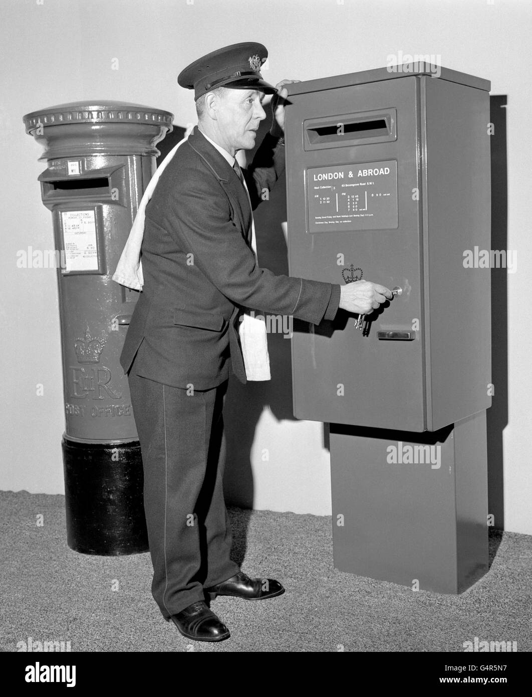Postman Douglas Dibb tries out the new type of pillar box under consideration by the Post Office at the GPO headquarters, London. The new box has rectangular panels as opposed to the familiar round or oval shaped boxes Stock Photo