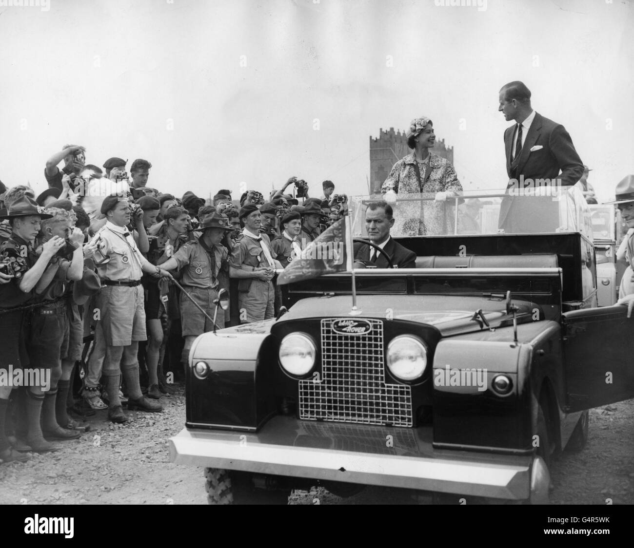 Queen Elizabeth II and the Duke of Edinburgh drive in an open Land Rover through the World Scout Jubilee Jamboree camp in Sutton Park, Warwickshire. Thirty-four thousand Scouts from eighty-three countries attended the Jamboree, which celebrates the golden jubilee of the Scout movement and the birth centenary of Lord Baden-Powell. Stock Photo