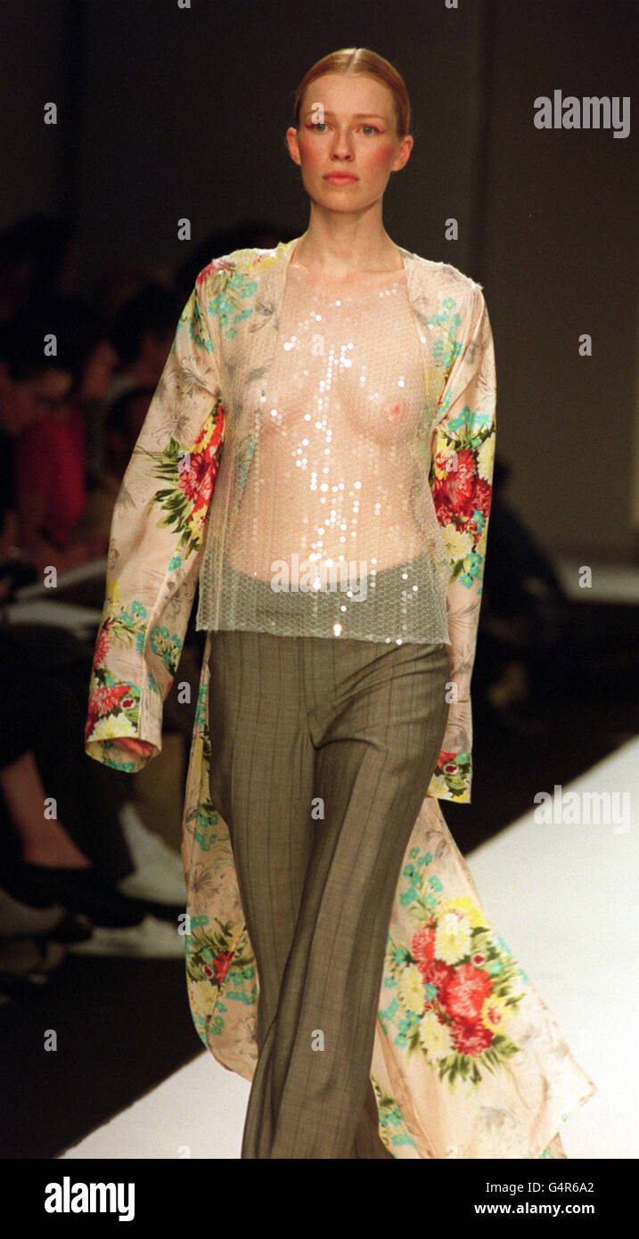 A model presents a full-length flowerprint coat, see-through sequined top and green pinstripe flared tousers on the catwalk during the New Zealand Four show as part London Fashion Week Stock Photo -