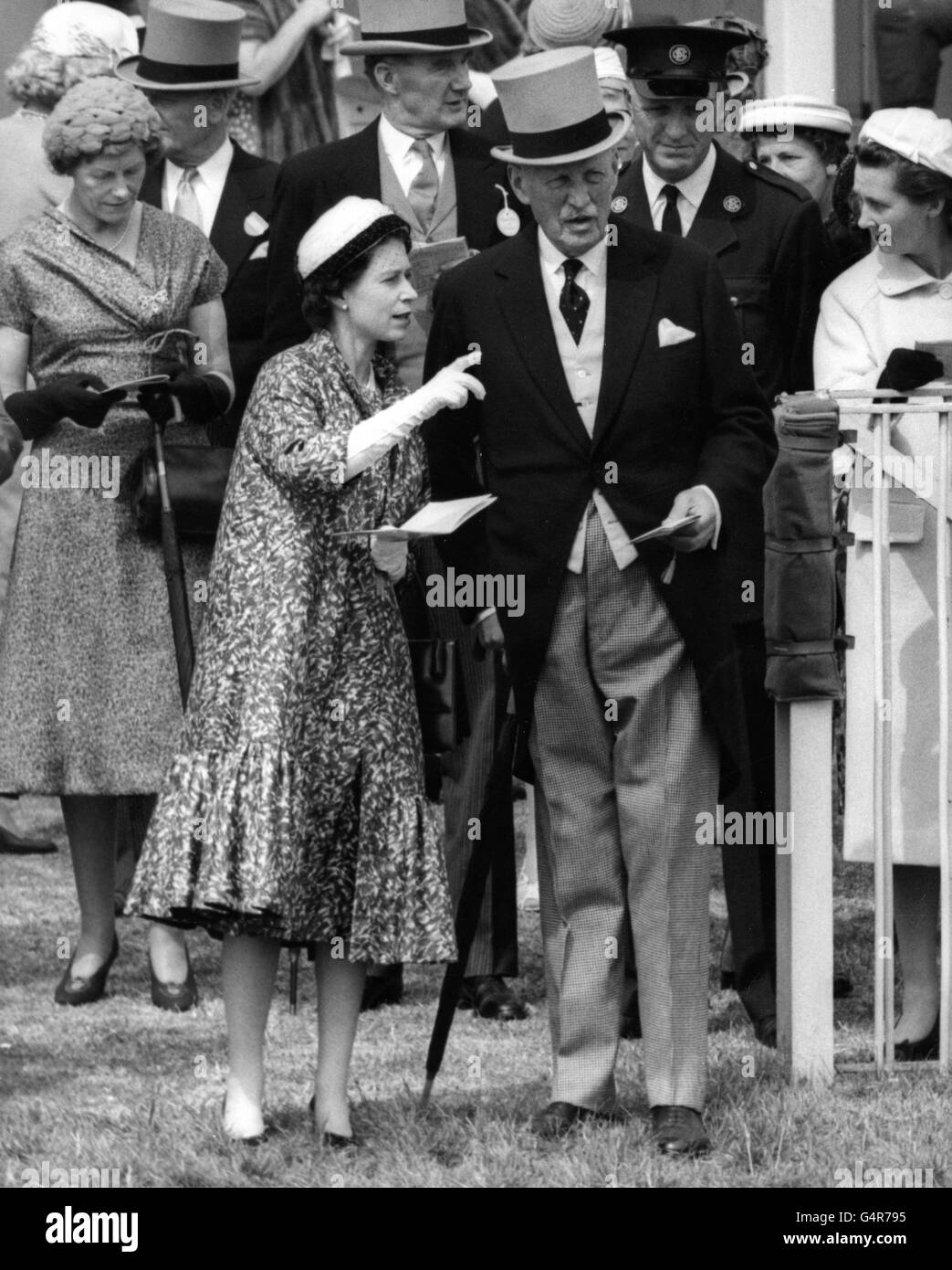 Queen Elizabeth II points as she talks to her racing manager, Captain Charles Moore, at Epsom, where they were watching the parade of fillies for the Oaks. Stock Photo