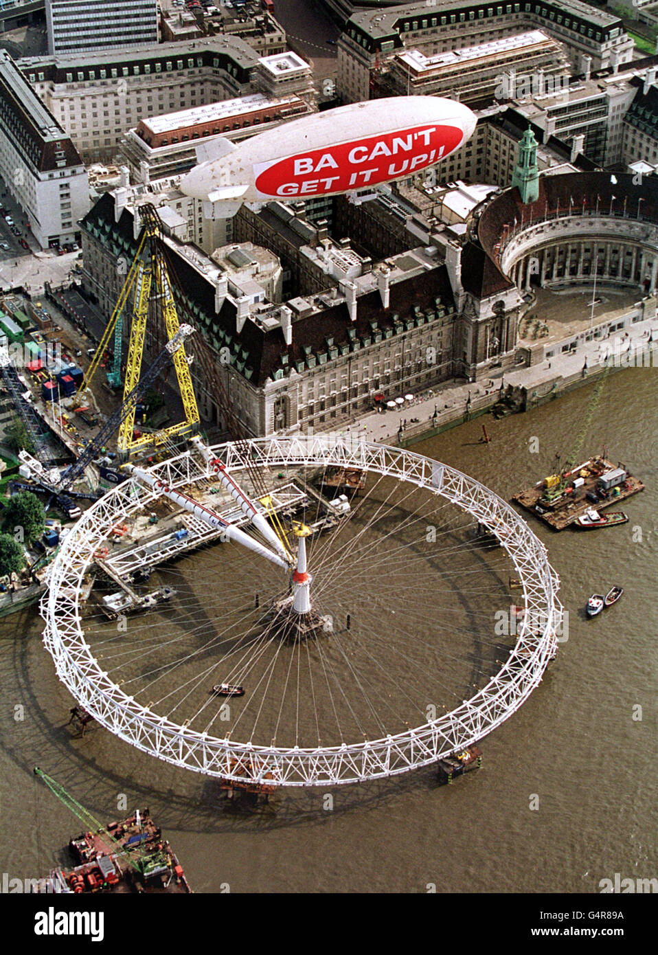 London Buildings and Landmarks - The Millennium Wheel - 1999. A Virgin light airship flies over the still horizontal Millennium Wheel (The London Eye) in central London . Stock Photo