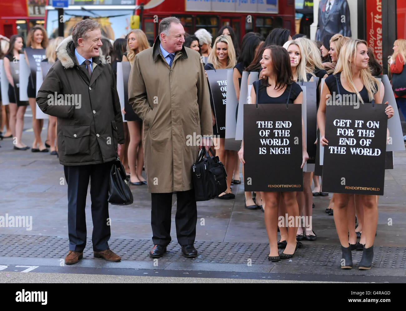 Two men speak to models promoting the launch of Lynx 2012 Final Edition body spray, at Piccadilly Circus, in central London. Stock Photo