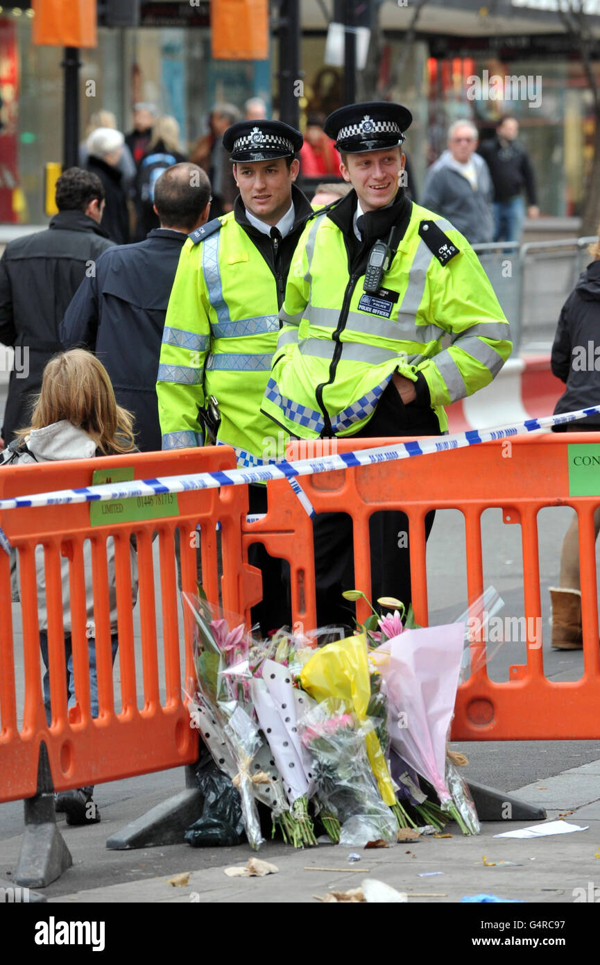 Police stand behind flowers laid near the scene where Seydou