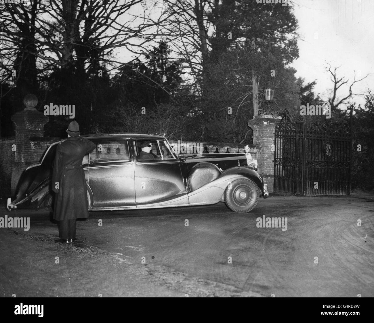 A policeman salutes as the car bearing Queen Elizabeth II and the Duke of Edinburgh arrives at the Jubilee Gate of Sandringham House. It was expected that following the Queen's arrival, the body of King George VI would be taken to St. Magdalene Church, Sandringham, lying in state until being brought to London. Stock Photo