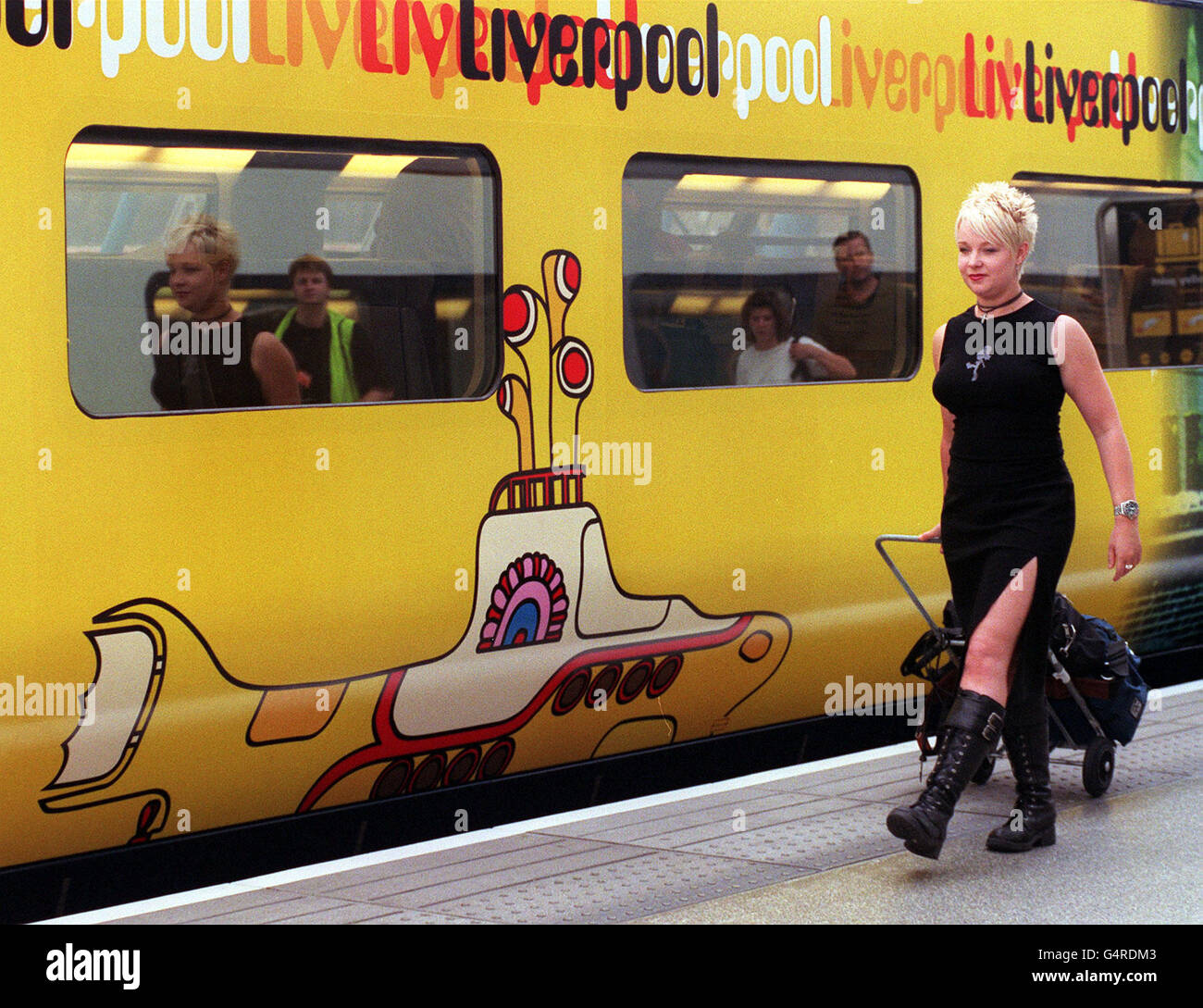 A passenger rushes to board a newly painted Euro Star train at Waterloo Station in London. The train has been decorated with images from the revamped Beatles' film Yellow Submarine and renamed the Beatles Express. Stock Photo