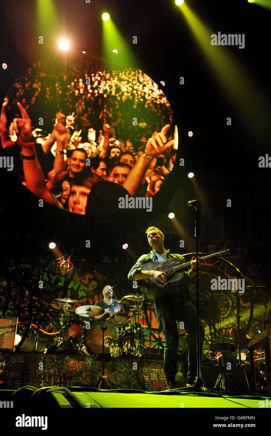 Chris Martin (front) and Will Champion of Coldplay performs as they promote their fifth studio album, Mylo Xyloto, released earlier this year, at The O2 Arena, Greenwich, south London. Stock Photo