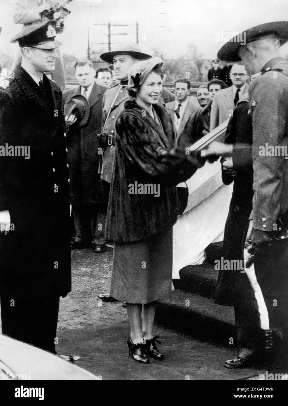 Princess Elizabeth stops to shake hands with a Royal Canadian Mounted Police officer on her arrival of Dorval Airport, Montreal with the Duke of Edinburgh Stock Photo