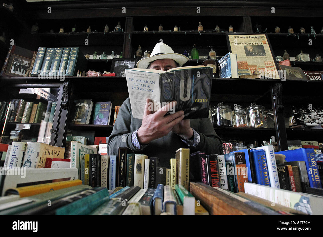 Dermot O Donoghue reads in Sweny's pharmacy in Dublin, made famous by the book 'Ulysses' by James Joyce, used today as a James Joyce heritage centre during a celebration of his work 'The Dead' on the anniversary of the date the story takes place on the evening of the Feast of the Epiphany on January 6th, 1904. Stock Photo