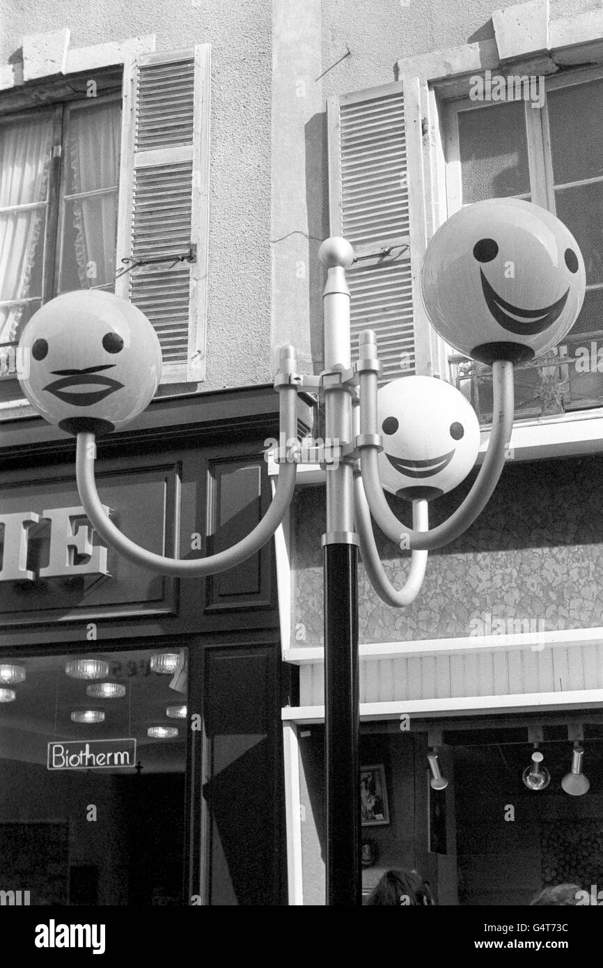 Brightening up street lamps in the Rue du Chateau, Cherbourg, are these amusing faces, an official permanent feature of a shopping area Stock Photo
