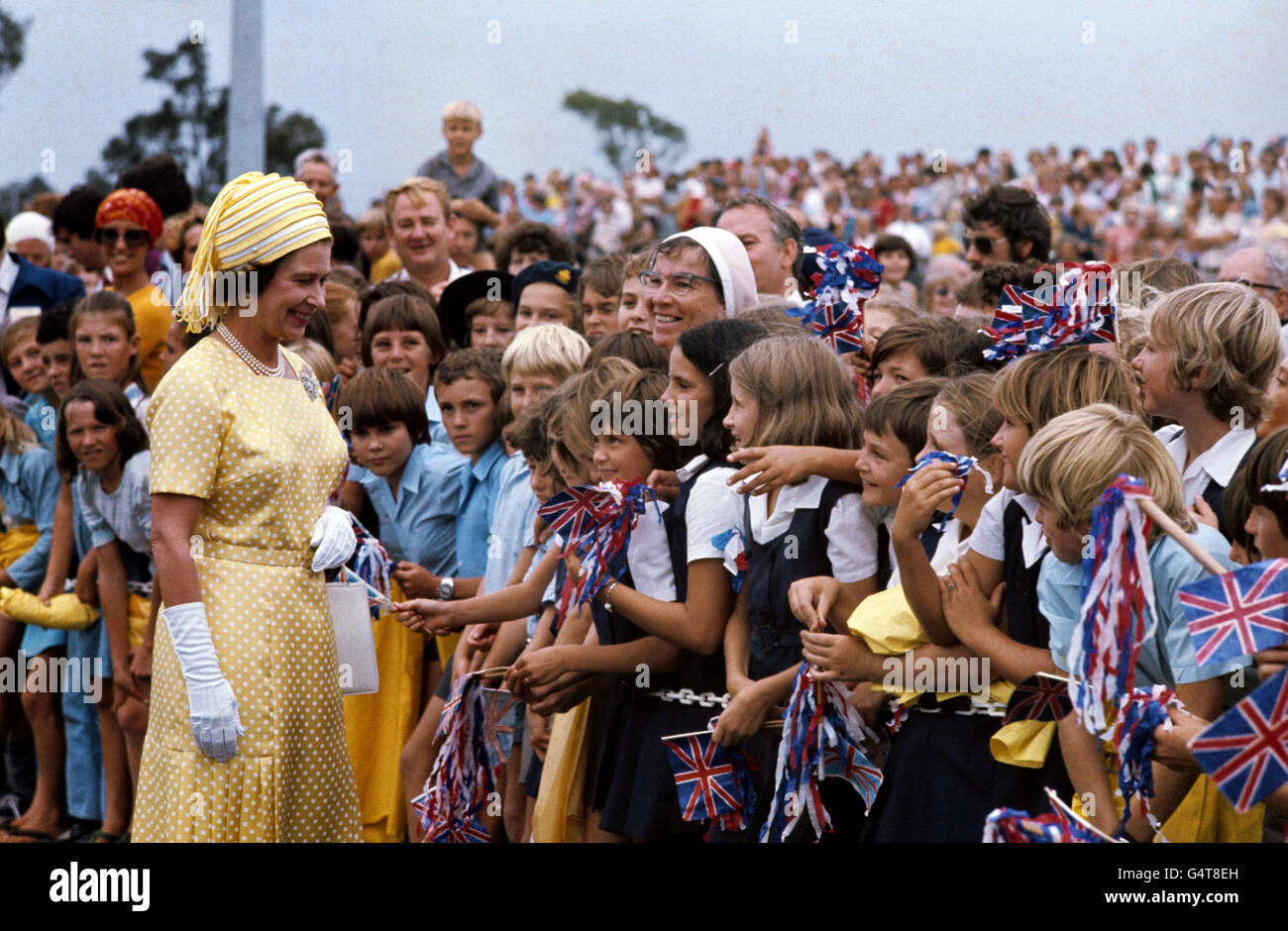 The Queen meets flag-waving school children on arrival at Brisbane, during her Silver Jubilee Tour of Australia. Stock Photo