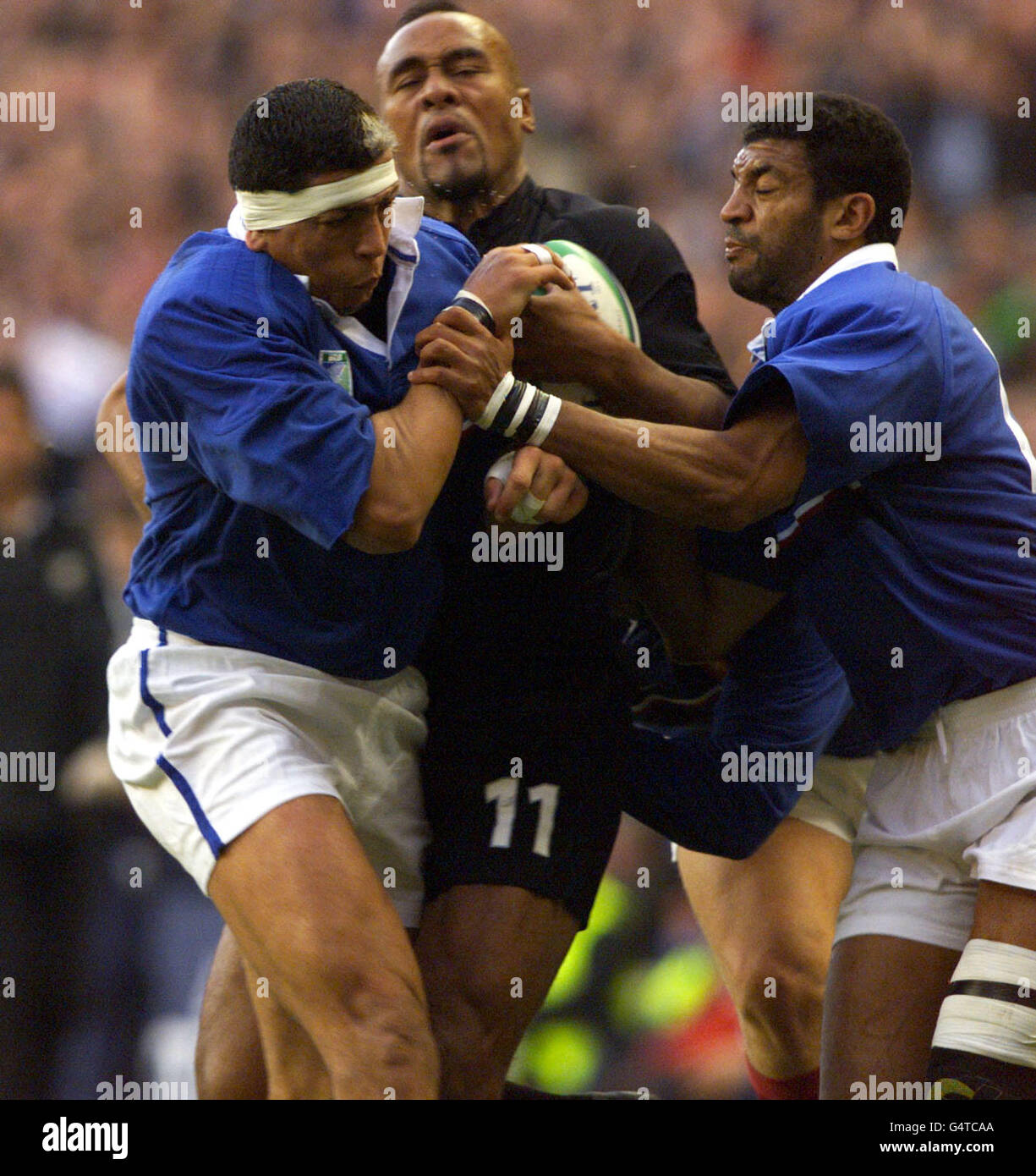 New Zealand All Blacks winger Jonah Lomu is held up for a moment before breaking through France 's defence of Abdelatif Benazzi (left) and Emile Ntamack (right) to score a try at Twickenham, in London, during the Rugby World Cup semi final match. Stock Photo