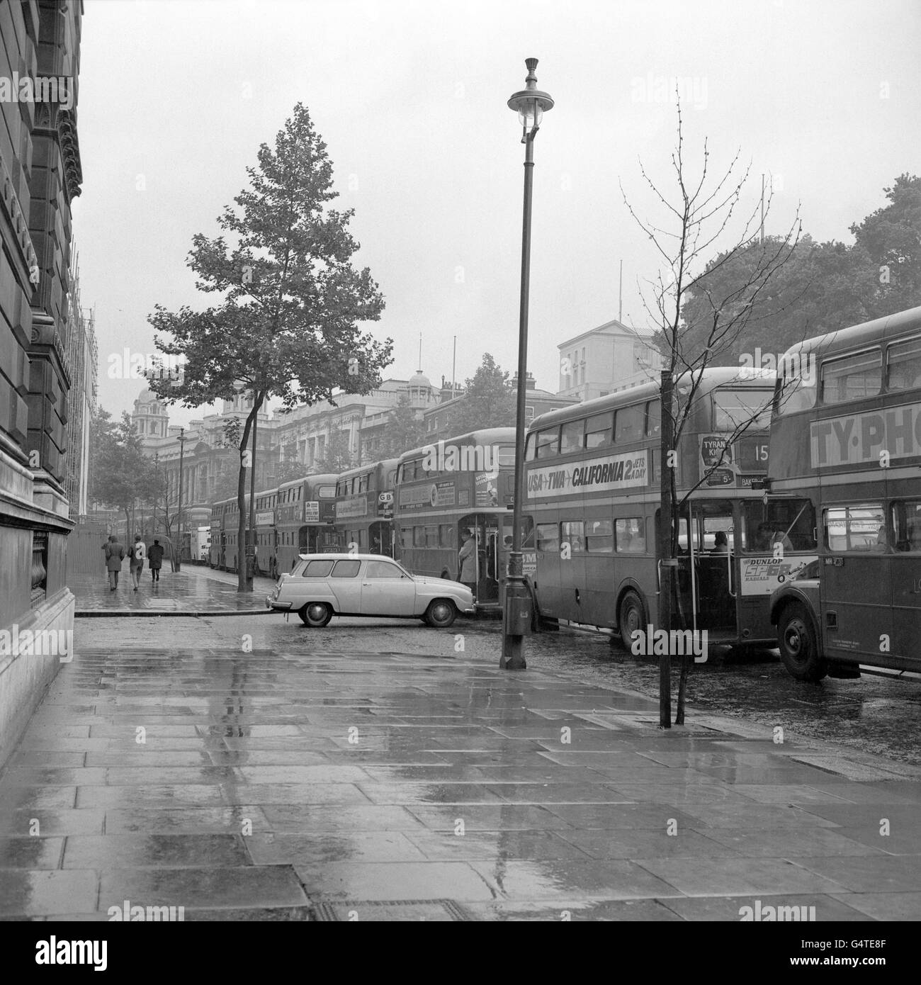 A lone Saab car waits to be let out of a side street as buses full of commuters pile into London. Buses were fuller than normal and traffic worse than usual due to the current go-slow on the part of British Rail workers Stock Photo