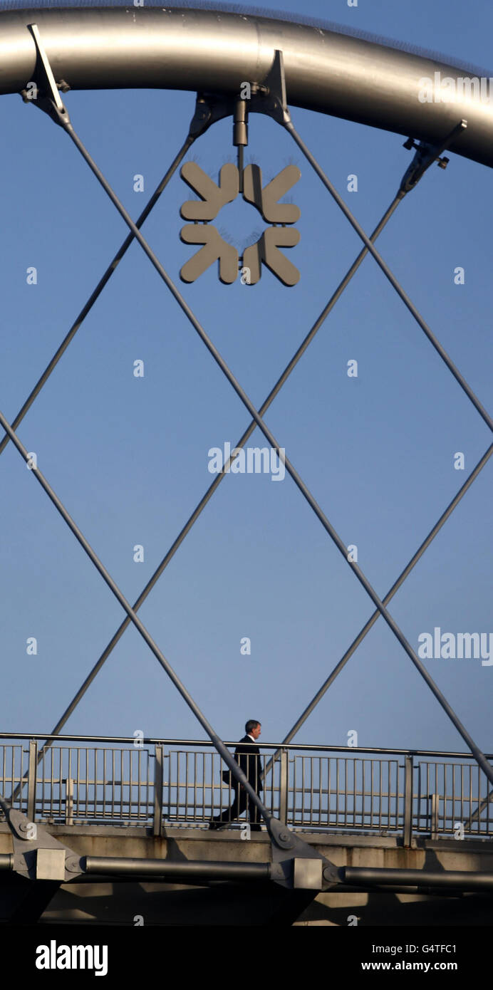 A man walks past an RBS sign at the Royal Bank of Scotland headquarters at Gogarburn in Scotland. Stock Photo