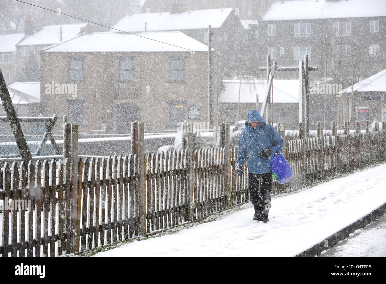 A woman walks back from the local shop in the snow at Nenthead, Cumbria, as the country braced itself for a spell of cooler weather that has brought snow to some regions. Stock Photo