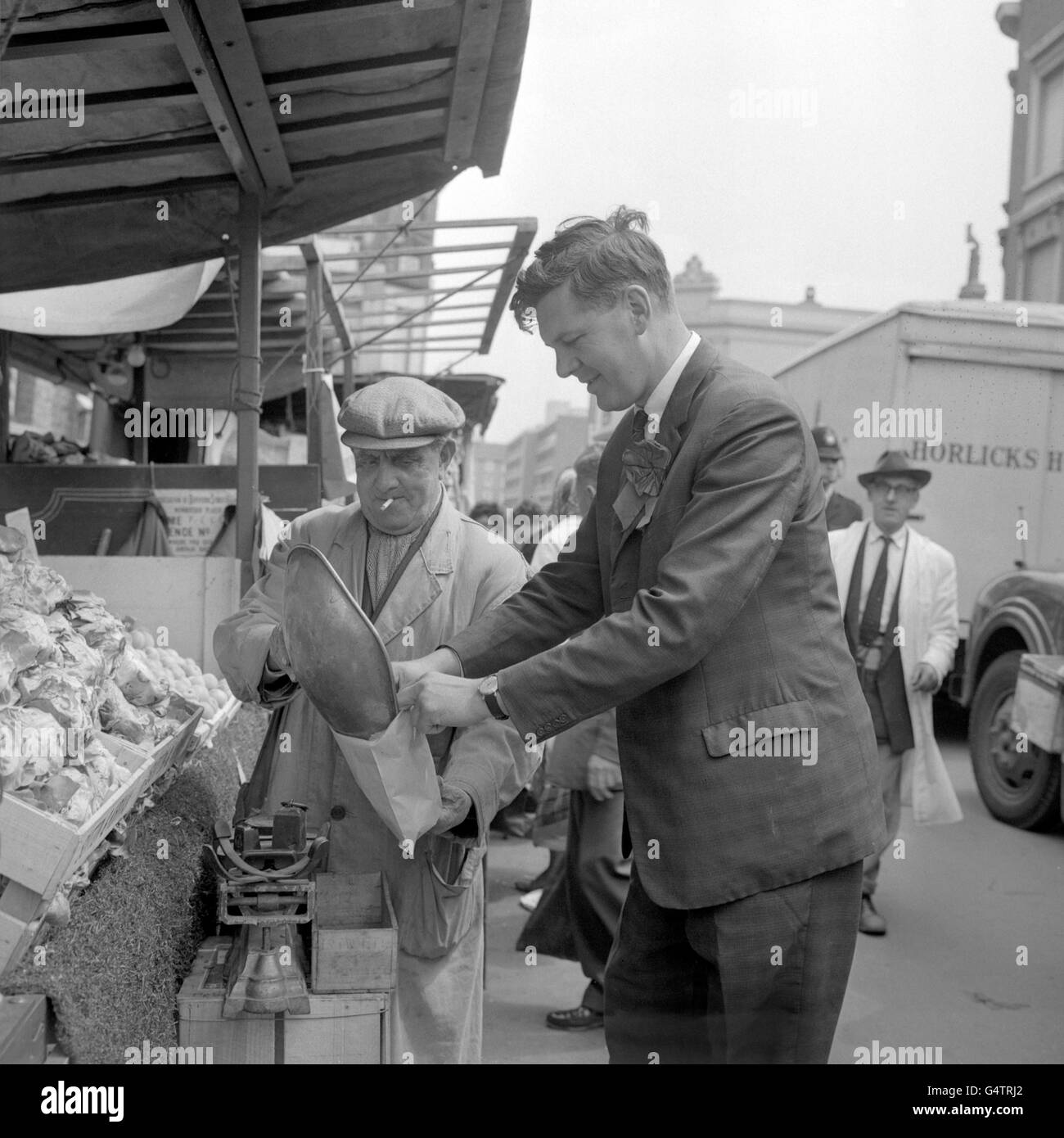 Conservative politician John Brimacombe makes a purchase from street trader James Marchant in his constituency of Deptford, South London, before the by-election in a few days Stock Photo