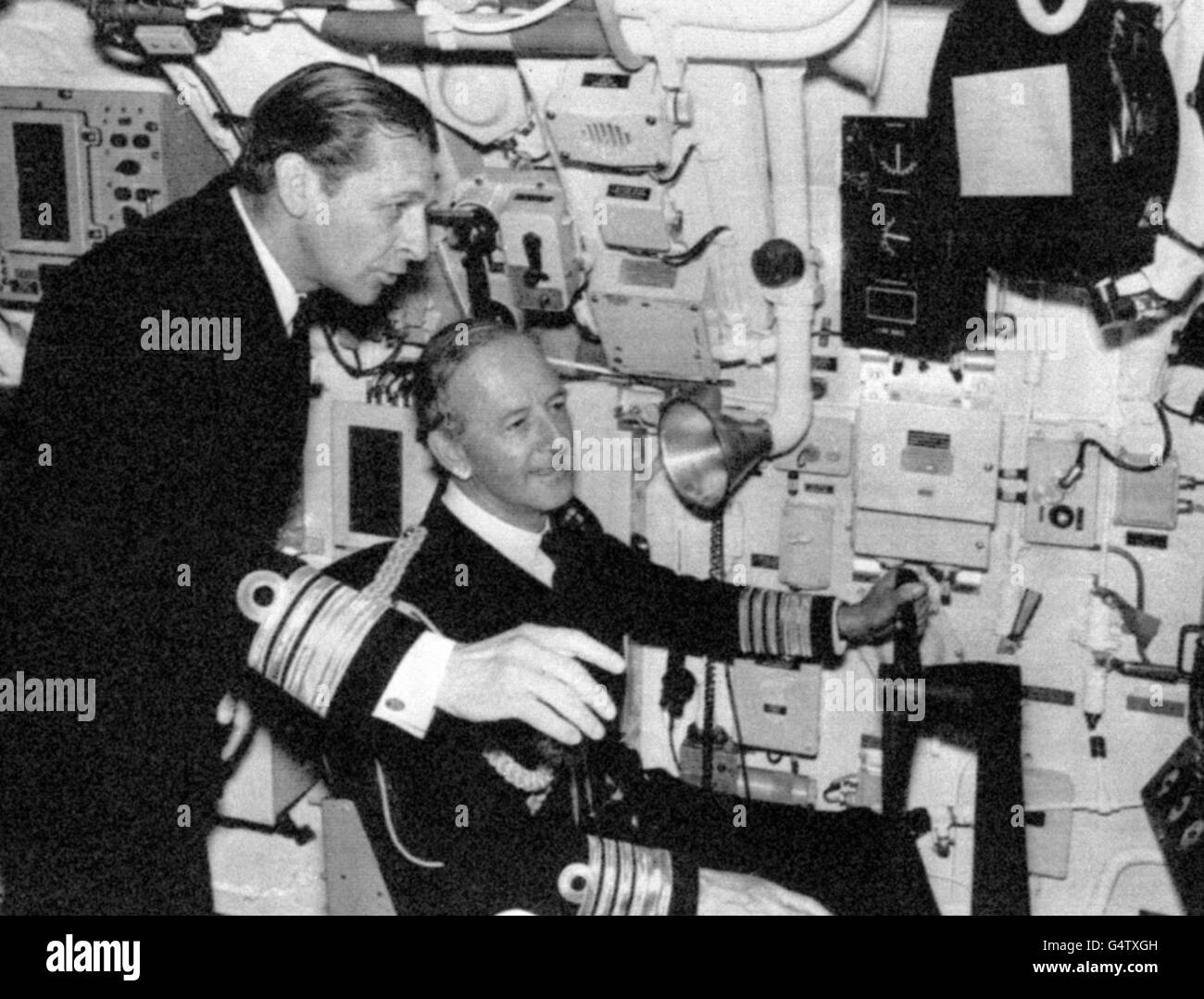 At the commissioning of HMS Sovereign, the Royal Navy's eighth nuclear submarine to come into service, Vice Admiral Iwan Raikes (l), the new Flag Officer Submarines, explains the ship's control panel to the seated First Sea Lord, Admiral Sir Edward Ashmore. Vice Admiral Raikes is official adviser on submarine matters tot he Admiralty Board. Stock Photo