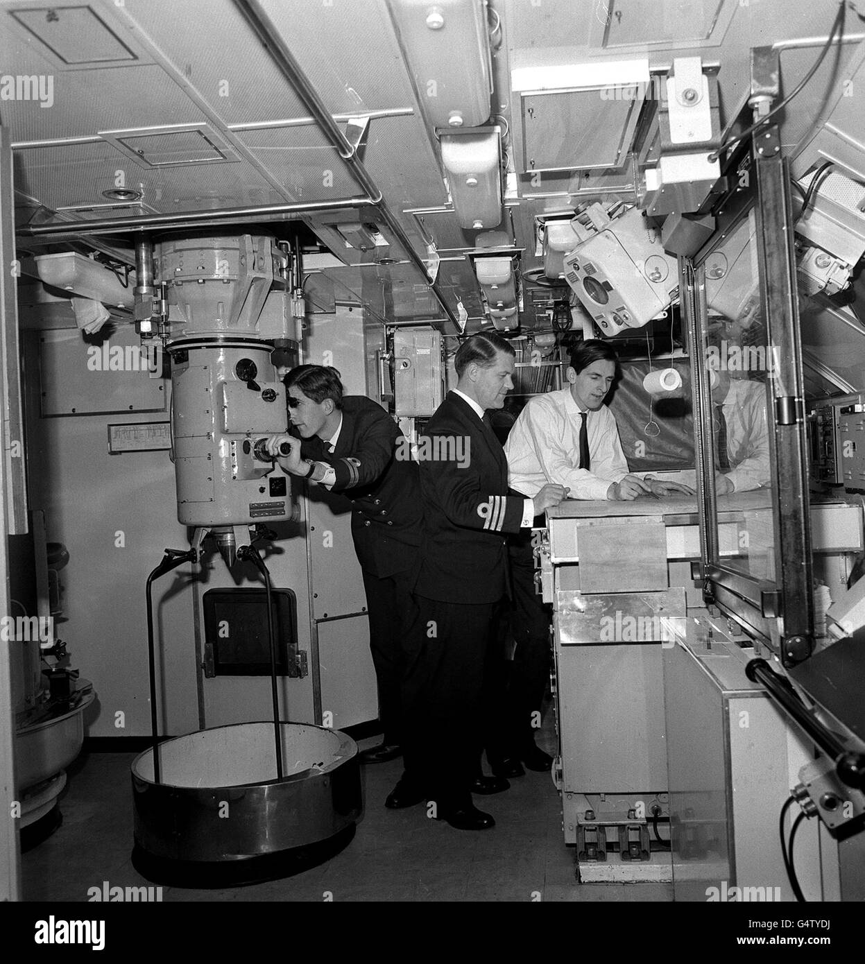 The Nuclear powered submarine Valiant at Portsmouth. Commander Herbert and Lieutenant P.Q.Stevens are studying the navigation chart. On left Lieutenant C.W.Hunter is on the periscope. The submarine was visiting Portsmouth after four months of trials. Stock Photo