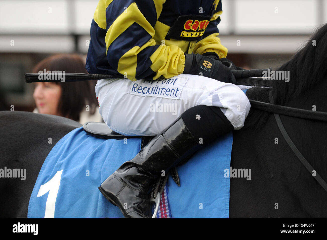 Detail of a jockey holding his whip whilst seated on his ride Stock