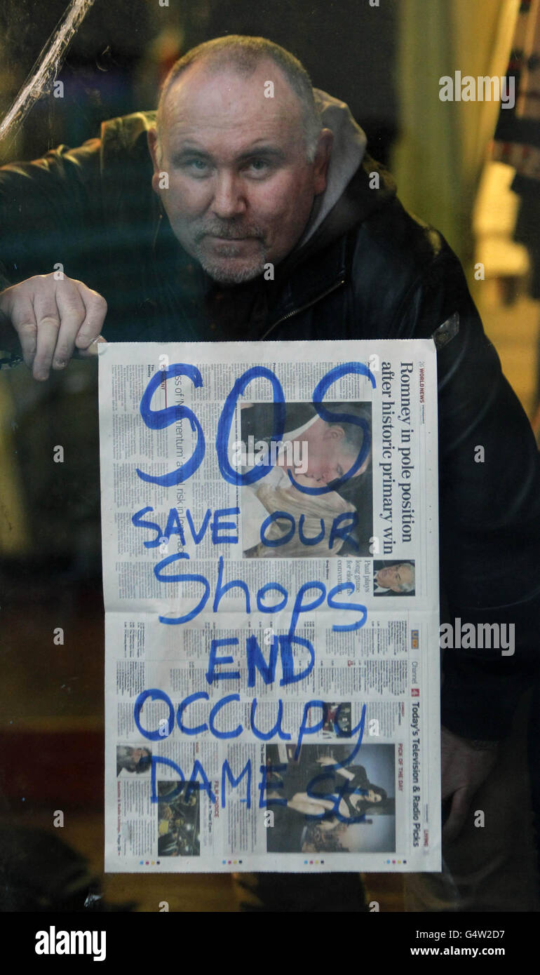 Frank McQuade, who owns three clothes shops on Fownes Street in Dublin's Temple Bar, puts up posters calling for the Occupy Dame Street camp to be dismantled. Stock Photo