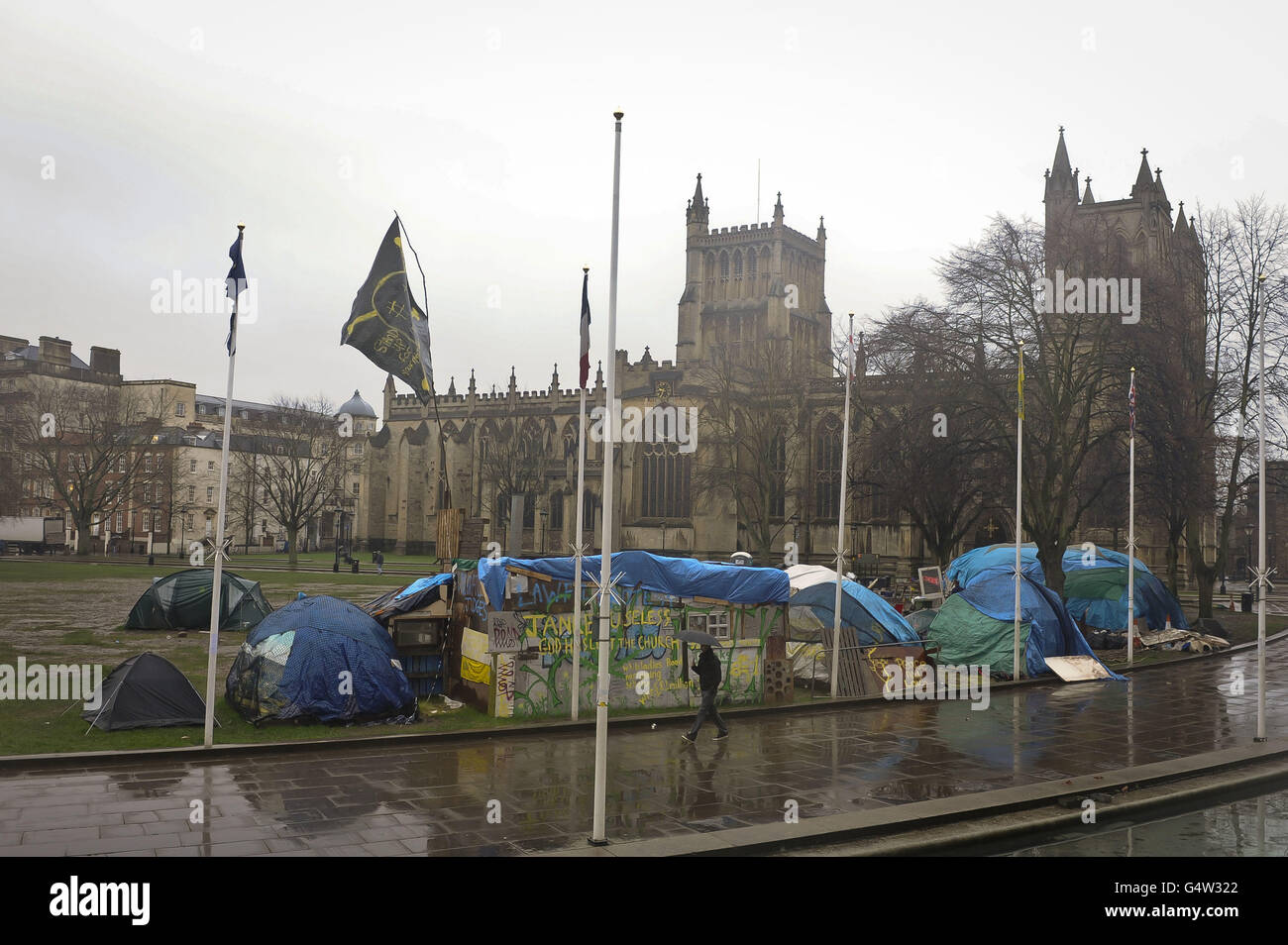 A man walks past tarpaulin structures on College Green, Bristol, where the Occupy Bristol movement have been camped since October 2011. Stock Photo