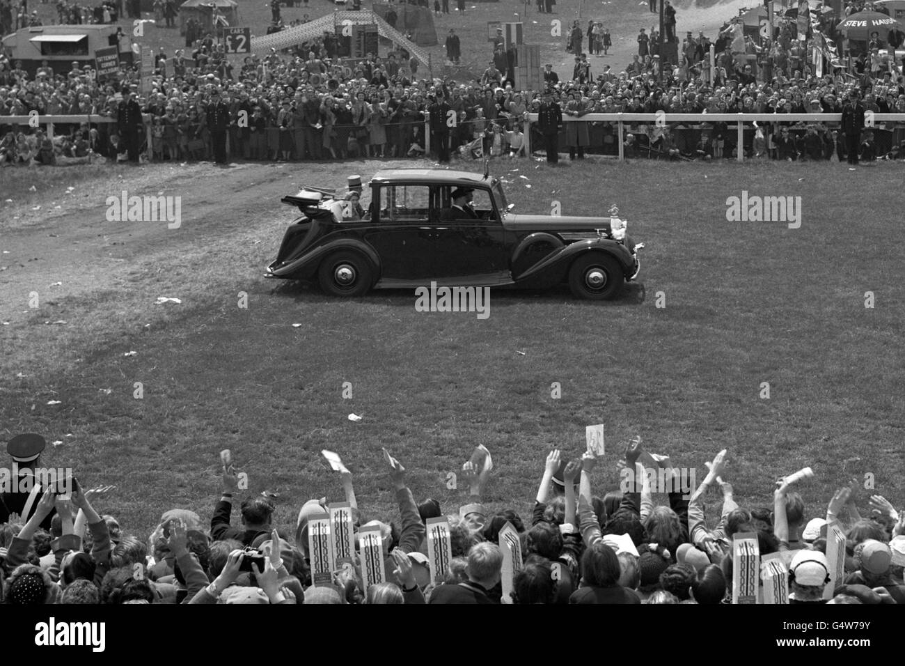 The Queen drives along the course at Epsom in front of the waving and cheering crowd Stock Photo