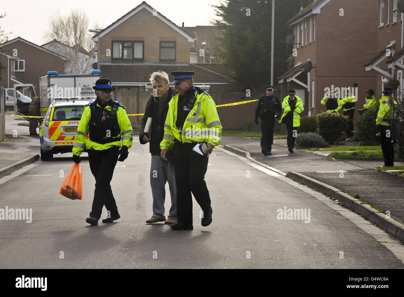 Police escort a resident to safety inside a police cordon on Cunningham Road, adjacent to Beatty Way, Burnham on Sea in Somerset after police arrested a man under the Explosives Act. Stock Photo