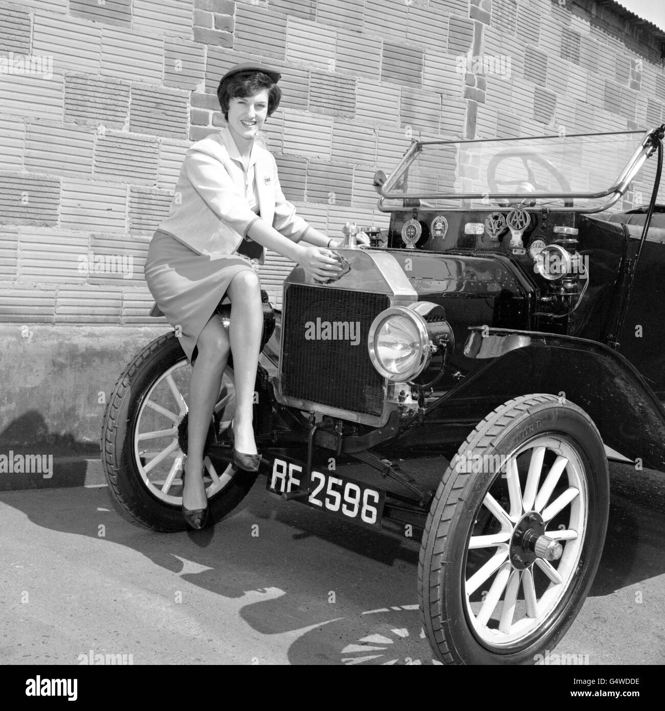 Trans World Airlines hostess Carolyn Forster of Middlesex, who hunts for vintage motor vehicles when not in the air. After finding the old cars, like this 1912 Ford Model T, she photographs them for record Stock Photo