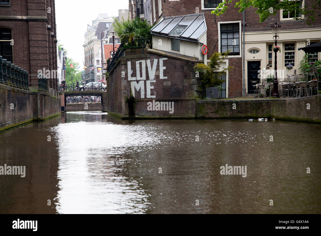'LOVE ME' graffiti on the wall of a waterway canal in Amsterdam. Stock Photo