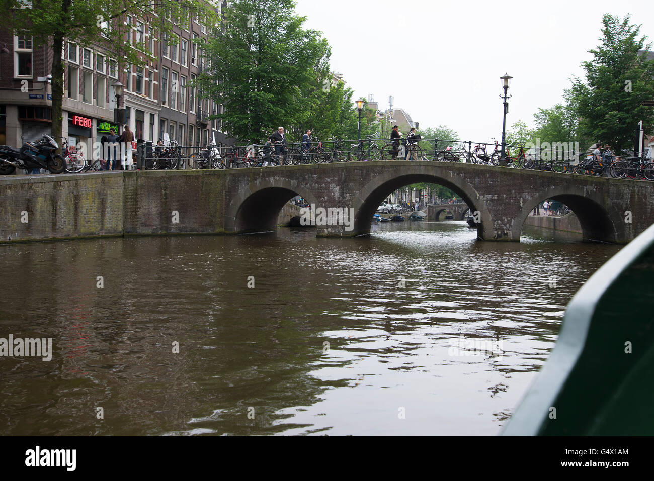 Amsterdam Prinsengracht triple arch bridge people walk walking cross crossing over canal. Stock Photo
