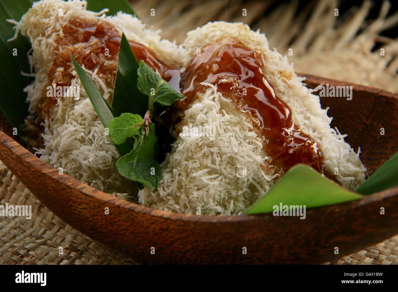 Lupis, traditional Javanese glutinous rice cake with grated coconut and palm sugar syrup. Plated in contemporary Javanese set. Stock Photo