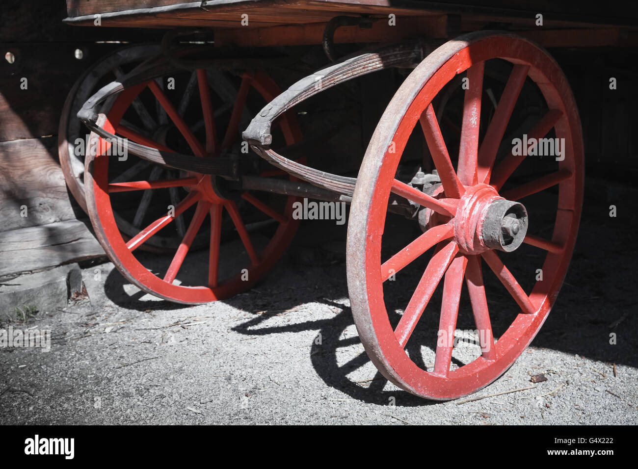 Fragment of an old wooden cart with red wheels Stock Photo