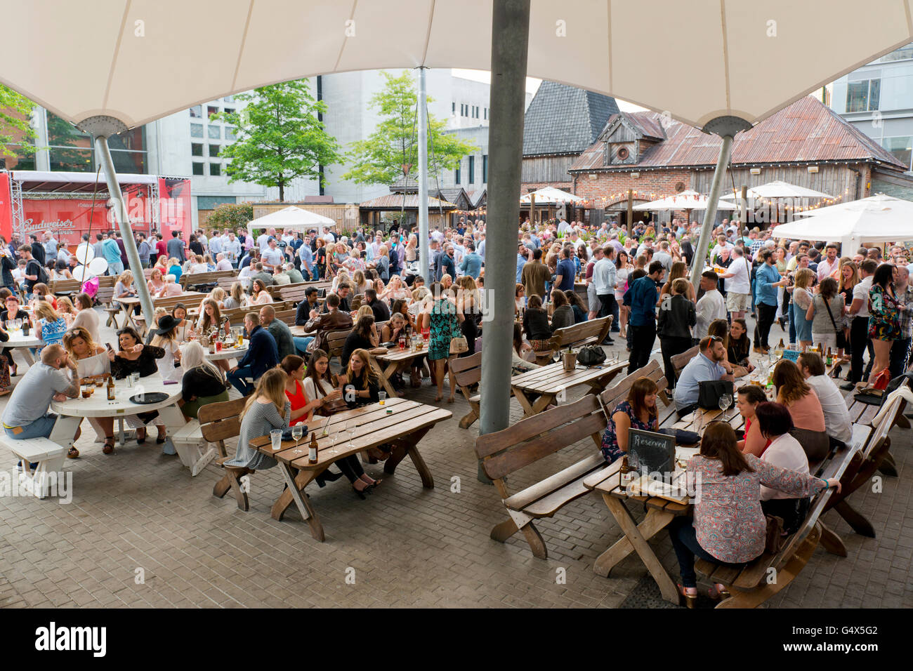 Revellers enjoy the ambiance of the beer garden at the Oast House Restaurant and Bar in the Spinningfields area of Manchester. Stock Photo