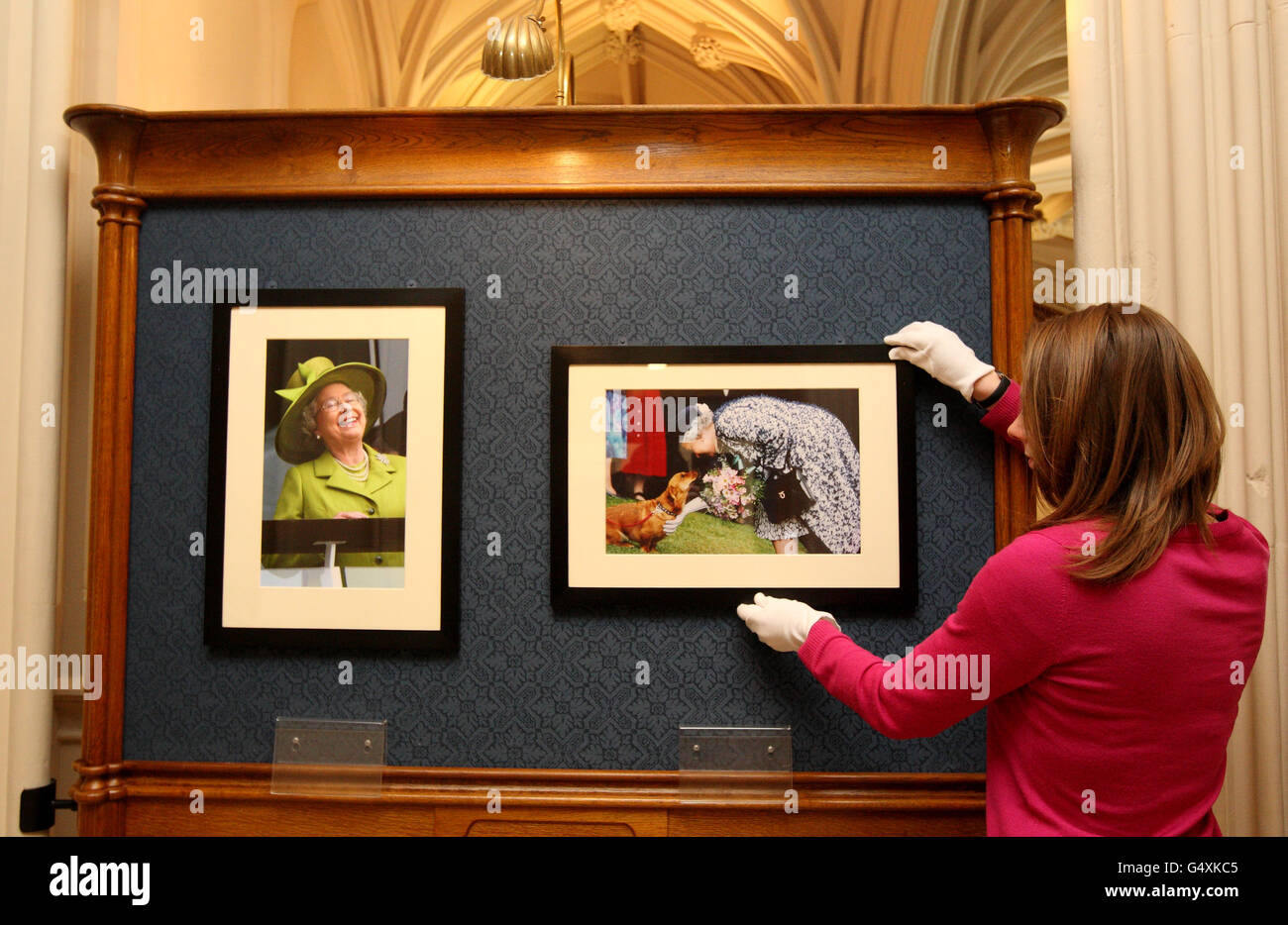 Royal Collection employee Alice Ross hangs a photograph from the Hexham Courant (right) taken in 1998 of the Queen when she visited Vindolanda Roman Fort on Hadrian's Wall when she meets Watney who is a Dorgi which was bread by The Queen two years previously, and given to Lady Beaumont. The photograph is part of The Queen: 60 photographs for 60 years exhibition at Windsor Castle. Stock Photo