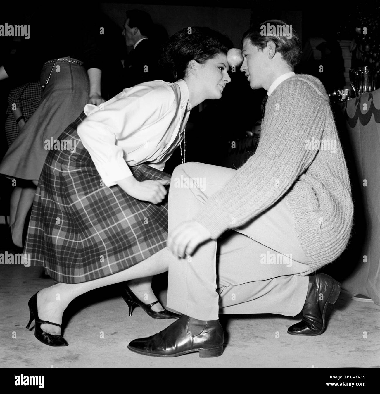 A new dance, the Apple Twist, demonstrated by Colin and Sidney Wilson at a London party. The Apple twist danced to a beat rhythm whilst the dancers have to keep the apple between their foreheads. Stock Photo