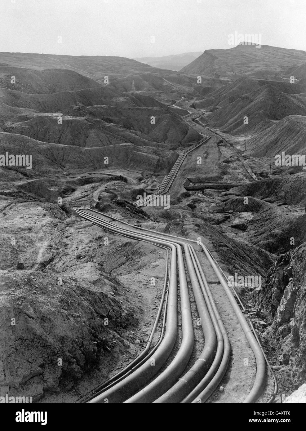 Pipelines belonging to the Anglo-Iranian Abadan oil refinery weave through the mountainous oilfield area of Persia, Iran Stock Photo
