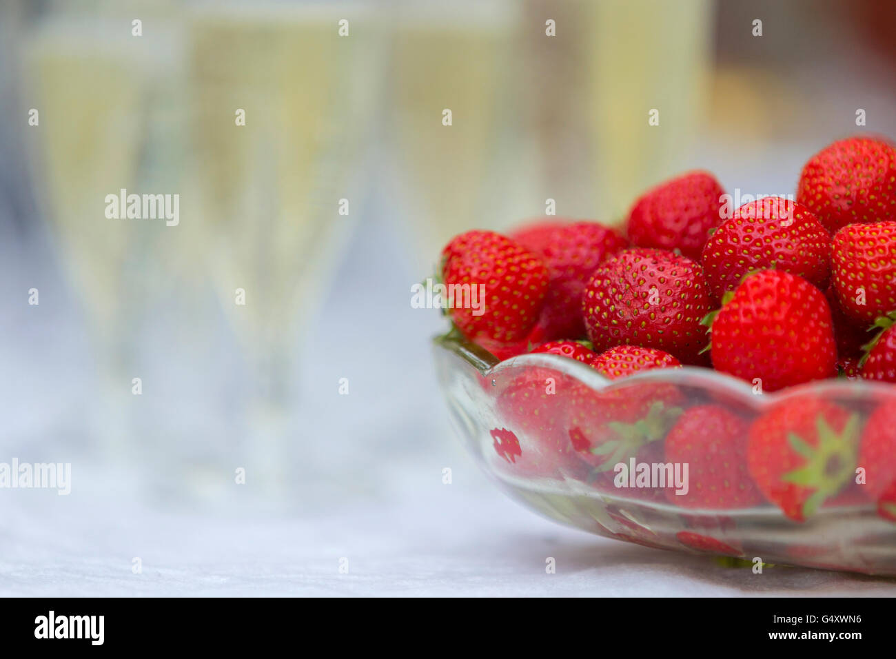 A bowl of strawberries and a few glasses of champagne on top of a table, Sweden. Stock Photo